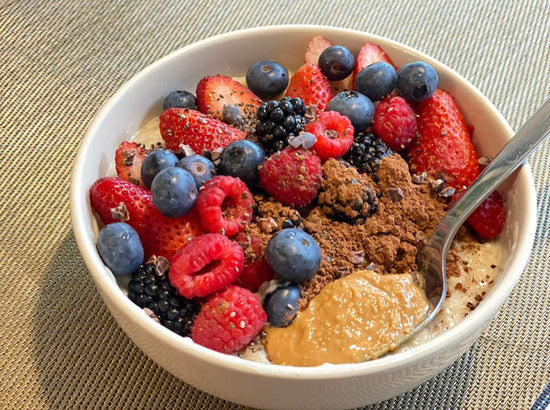 Eine Schüssel proteinreicher Overnight Oat mit Schokoladenproteinpulver, Beeren, Heidelbeeren, Erdbeeren und 1 EL Honig.